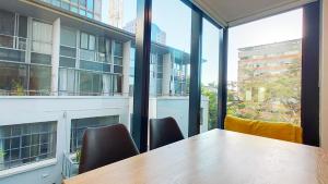 a table and chairs in a room with a large window at Sky Stars Essential Home in Auckland