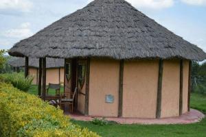 Cabaña pequeña con techo de paja y silla en The Great Circle Lodge, en Nanyuki