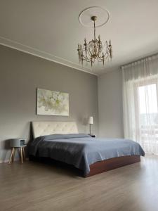 Habitación blanca con cama y lámpara de araña. en Bella Vita Guesthouse -parcheggio privato interno, en Arona