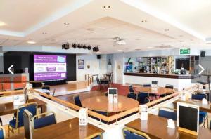 a restaurant with tables and chairs and a large screen at 49 Bayside Cove Pevensey Bay Holiday Park in Pevensey