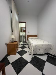 sypialnia z łóżkiem i czarno-białą podłogą wyłożoną szachownicą w obiekcie Hostal Los Amigos w mieście Siruela