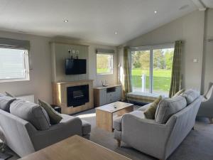 uma sala de estar com dois sofás e uma televisão em 42 Woodland Walk Pevensey Bay Holiday Park sleeps 6 em Pevensey