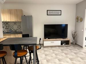 sala de estar con TV, mesa y sillas en Résidence Alba en Bonifacio