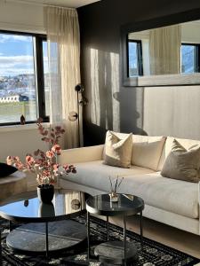 a living room with a white couch and two tables at TotalApartments Vervet Gjøa, brand new apartments in Tromsø