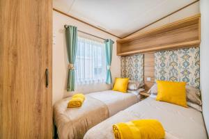 two beds in a small room with yellow pillows at Your Ultimate Holiday Rental at Pevensey Bay 35 Woodland Walk in Pevensey
