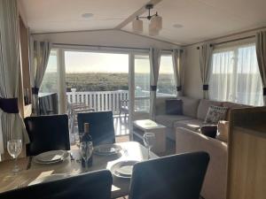 a living room with a couch and a table and chairs at 74 Bayside Cove Pevensey Bay Holiday Park in Pevensey