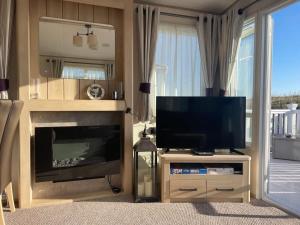 a living room with a television and a fireplace at 74 Bayside Cove Pevensey Bay Holiday Park in Pevensey