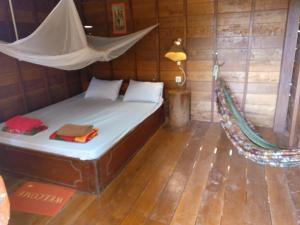 Una cama en una habitación con una hamaca. en FamilyHouse & Trekking en Banlung