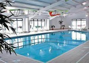 a large swimming pool with blue water in a building at 74 Bayside Cove Pevensey Bay Holiday Park in Pevensey