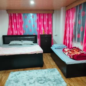 um quarto com 2 camas e cortinas cor-de-rosa em Pradhan's Homestay em Takdāh