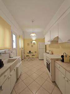 a large kitchen with white cabinets and a table in it at Caravin Wanderhome Acropolis, 1 min from Acropolis Museum in Athens