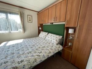 a bedroom with a bed and wooden cabinets at 27 Tower View Pevensey Bay Holiday Park in Pevensey