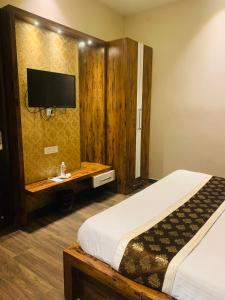 um quarto com uma cama e uma televisão na parede em Hotel New BMS pride em Amritsar