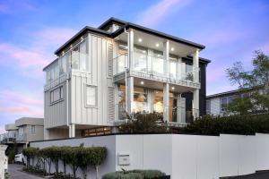 une maison avec une clôture blanche devant elle dans l'établissement The Bays Bed & Breakfast, à Auckland