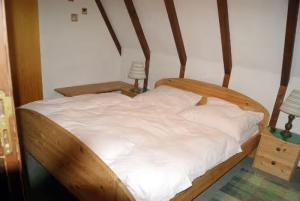 a bed with a wooden frame and white sheets at Ferienhaus Bergwiese in Siegsdorf