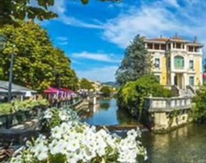 a river with flowers in front of a building at vintage home in L'Isle-sur-la-Sorgue