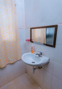 La salle de bains est pourvue d'un lavabo blanc et d'un miroir. dans l'établissement FARAJA HOMESTAY- Seamless Comfort in the Heart of the City - Free WiFi, Warm Hospitality, and Local Delights Await, à Moshi