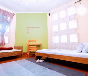 a bedroom with two beds and a table and two windows at FARAJA HOMESTAY- Seamless Comfort in the Heart of the City - Free WiFi, Warm Hospitality, and Local Delights Await in Moshi