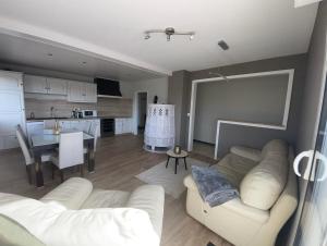 ein Wohnzimmer mit einem weißen Sofa und einer Küche in der Unterkunft Domaine Rosfelder - locations de gîte et cabane insolite in Gertwiller