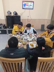 a group of people sitting around a table eating food at Great Himalayan Nature View Resort in Banjār