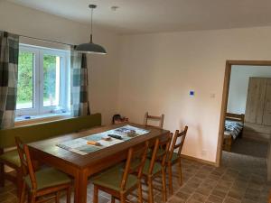 a kitchen with a wooden table with chairs and a dining room at Chata Holčovice in Nová Komora