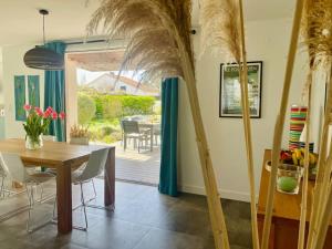 a dining room with a table and some palm trees at Villa Les coquelicots La Baule in La Baule