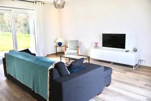 a living room with a blue couch and a tv at La Lumineuse in Tardinghen