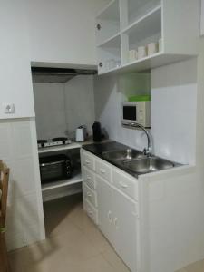 a white kitchen with a sink and a microwave at Casa da Romeira in Elvas