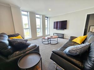 a living room with two leather couches and a table at Spacious & Luxurious Newtown Central in Wellington