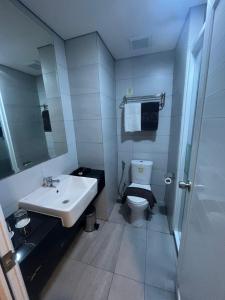 a bathroom with a sink and a toilet and a mirror at Zia Sanno Menteng Residences- Jakarta in Jakarta