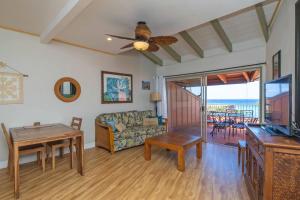 een woonkamer met een bank, een tafel en een televisie bij Kuleana Resort 207 in Kahana