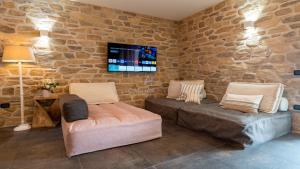 un soggiorno con 2 divani e una TV su un muro di pietra di Palladium Apt -Attico Vista Lago in centro Colombare, Sirmione a Sirmione