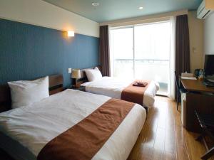 a hotel room with two beds and a window at Chateraise Lodge Atami in Atami