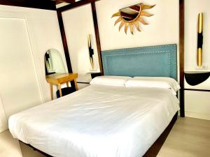 a bedroom with a white bed with a blue headboard at Apartamentos Real Suites Realejo in Granada