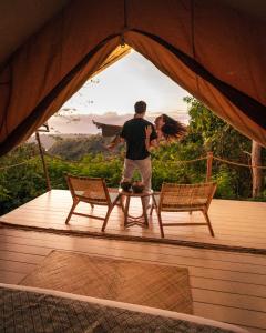 a man standing in a tent with two chairs at Autentik Penida "Glamping" - Adults only in Nusa Penida