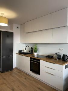 a kitchen with white cabinets and a black refrigerator at Apartament Browarna in Nowy Sącz