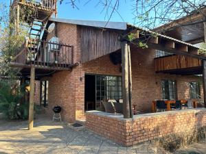 Bushveld Symphony Holiday Home في مارلوث بارك: مبنى من الطوب مع شرفة وفناء
