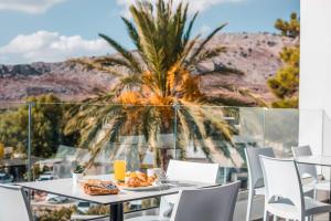 a table with a plate of food and a palm tree at Ellia Resort in Pefki