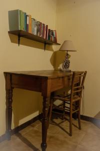 escritorio de madera con lámpara y estante con libros en Sa Domu de Ladiri GuestHouse 2.0, en Musei