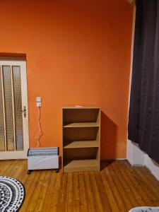 a room with an orange wall and a book shelf at Schick und Gemütlich in Ebenfurth