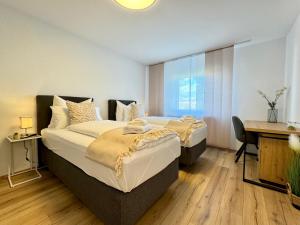 two beds in a hotel room with a desk and a desk at 3 Zimmer Apartment, 95 qm, max 5 Personen, Balkon, Garage, Internet 100 MBit in Leonberg