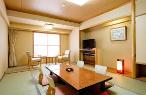 uma sala de estar com uma mesa e cadeiras e uma televisão em Yuzawa New Otani em Yuzawa