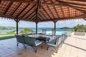 eine Terrasse mit einem Tisch, Stühlen und Meerblick in der Unterkunft Maison d'Ô Pointe Thalémont, avec petite crique privative in Le François