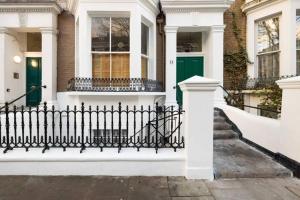 a black fence in front of a house at Magical 2-Bedroom Garden Apartment in Holland Park in London