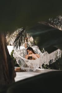 a woman sitting in a hammock on the beach at Autentik Penida "Glamping" - Adults only in Nusa Penida