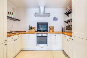 a kitchen with white cabinets and a stove at Bright 2BR Flat, 5 min to South Wimbledon Tube St in London