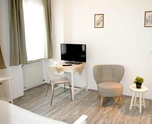 a room with a desk with a tv and two chairs at Hocher Hotel in Rothenburg ob der Tauber