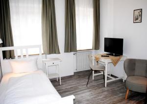 a bedroom with a bed and a desk with a television at Hocher Hotel in Rothenburg ob der Tauber