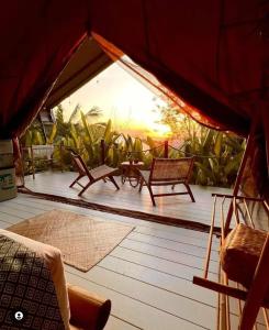 a screened in porch with chairs and a table at Autentik Penida "Glamping" - Adults only in Nusa Penida