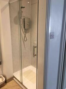 a shower with a glass door in a bathroom at The Post House (Centre of riverside village) in Stoke Gabriel